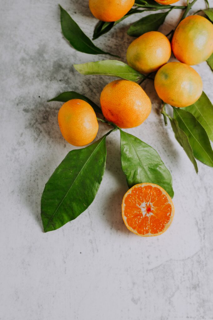 tangerines on the stem with one tangerine cut in half_fruits and vegetables to lower blood sugar
