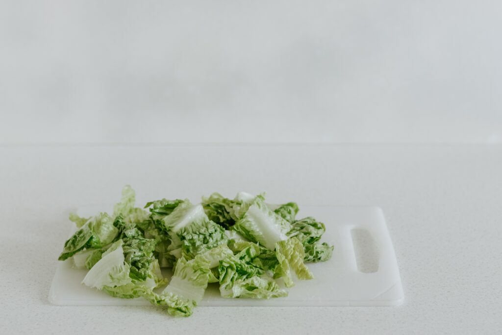 Chopped romaine lettuce on a white plastic cutting board.