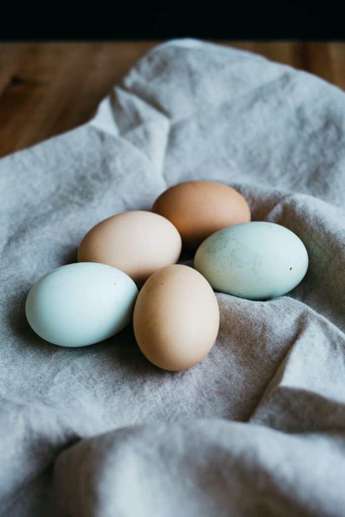Five eggs on a cloth. Three are beige colored and two are light blue.