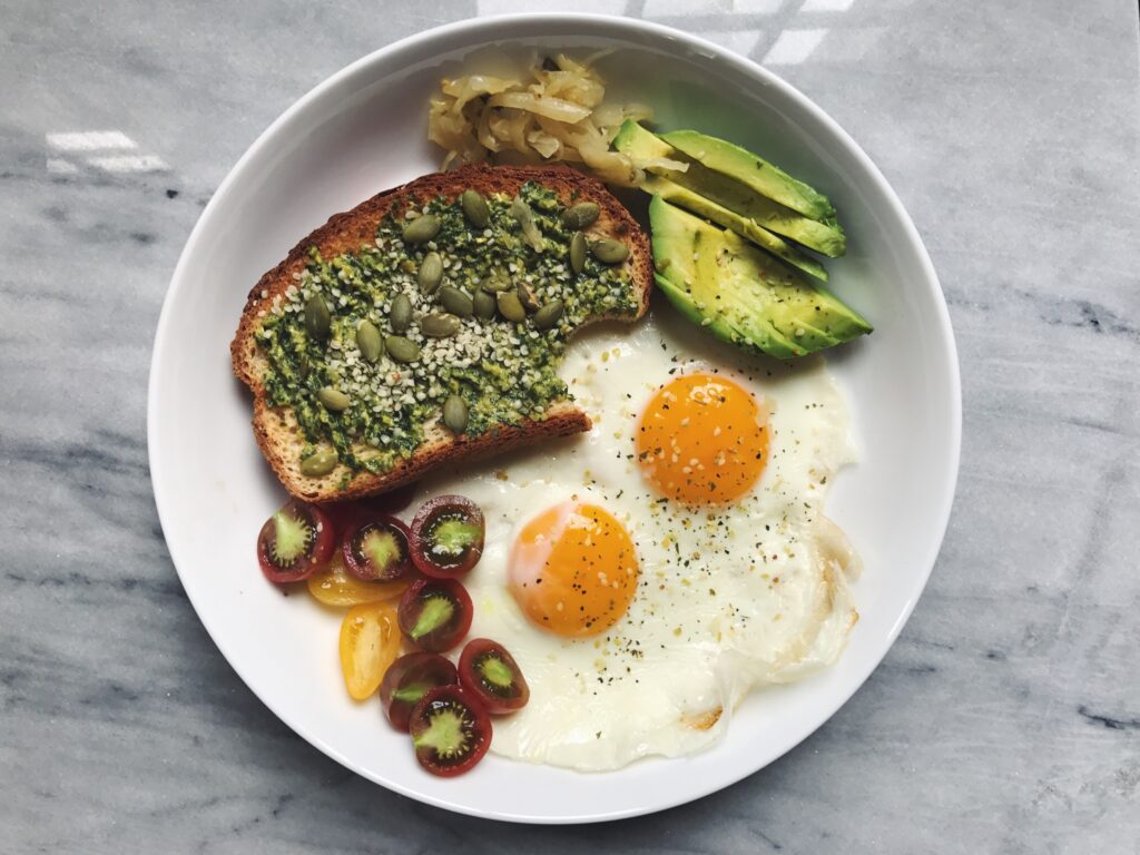 Breakfast plate of eggs, toast with pesto, avocado, tomatoes, and saurkraut_simple tips to lower daily stress